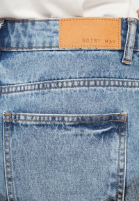 Τζιν παντελόνια από denim με ανοιχτό μπλε πλύση, διαθέτουν δερμάτινο έμβλημα με την επιγραφή "NOISY MAY" και πορτοκαλί ραφές στην πίσω τσέπη και τη μέση.