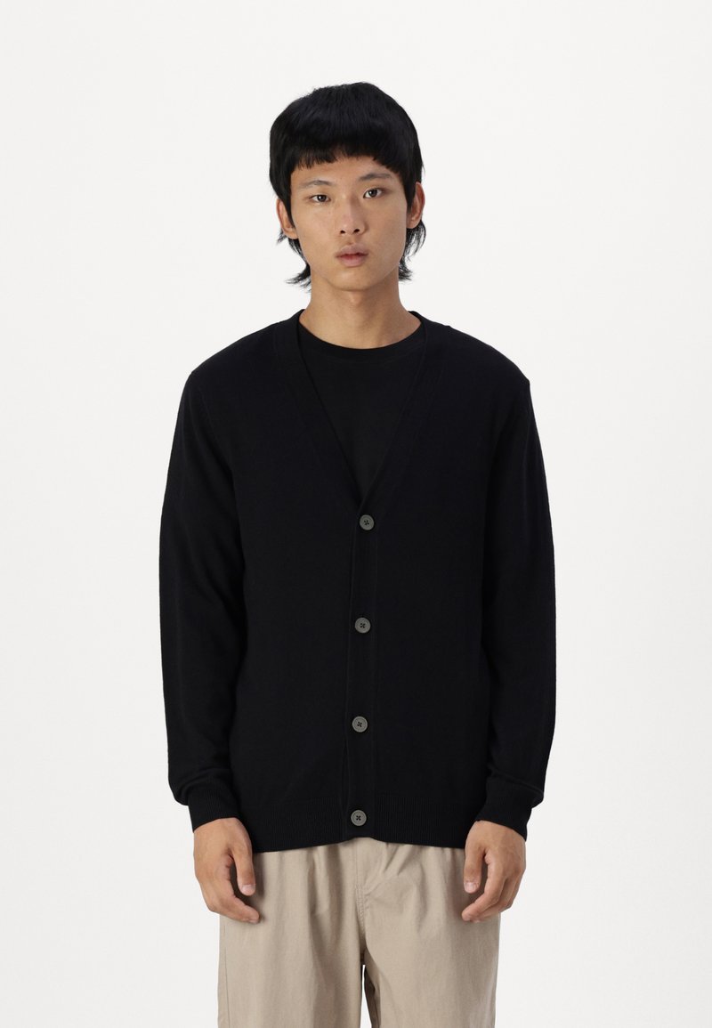 Svart cardigan laget av mykt stoff, med V-hals, lange ermer og seks frontknapper. Enkel design med ribbestrikkede mansjetter og nederkant.