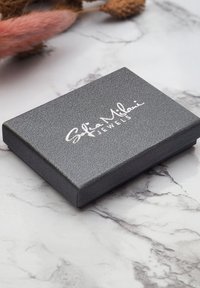 Grå texturerad smyckesask med ett slätt lock som har den präglade texten "Sofia Milani Jewels" i silver.