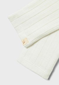 Tissu en crêpe côtelé avec de fines rayures verticales et de petits points texturés, avec une petite étiquette beige sur le bord.
