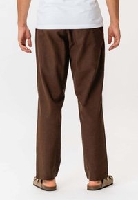 Brune bomuldsbukser med lige ben, der har sidelommer og en ren finish. Sammen med afslappede sandaler.