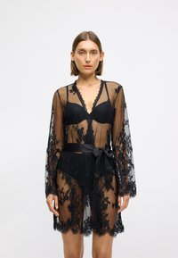 Svart blondekåpe med gjennomsiktig stoff, lange ermer, scallop-kant, blomsterbroderi og et satengbelte i midjen.