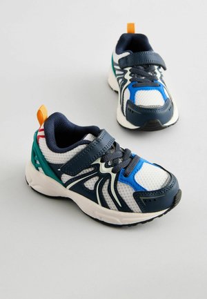 Sneakers med ett mesh vitt ovandel, marinblå accenter och grön hälstöd. Har en blå tåtröja, grå snören och en orange dragflik.