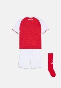 Un maillot de football rouge et blanc comprenant un maillot à motifs rouges avec logo, un short blanc et une chaussette rouge avec des accents blancs.