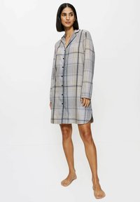 Šaty z kostkované látky v béžové a modré barvě, s límečkem, zapínáním na knoflíky, dlouhými rukávy a bočními rozparky pro pohodlí. Měkká textilie.