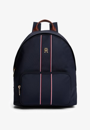 Marineblauwe nylon rugzak met handgreep van bruin leer en gouden logo. Voorzien van twee verticale rode en witte strepen en een voorvak met rits.