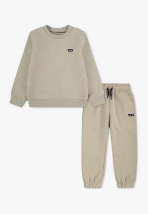 Beżowy zestaw dziecięcy: bluza i spodnie z elastycznym pasem, ściągaczami i logotypami Levi's na klatce piersiowej i udzie.