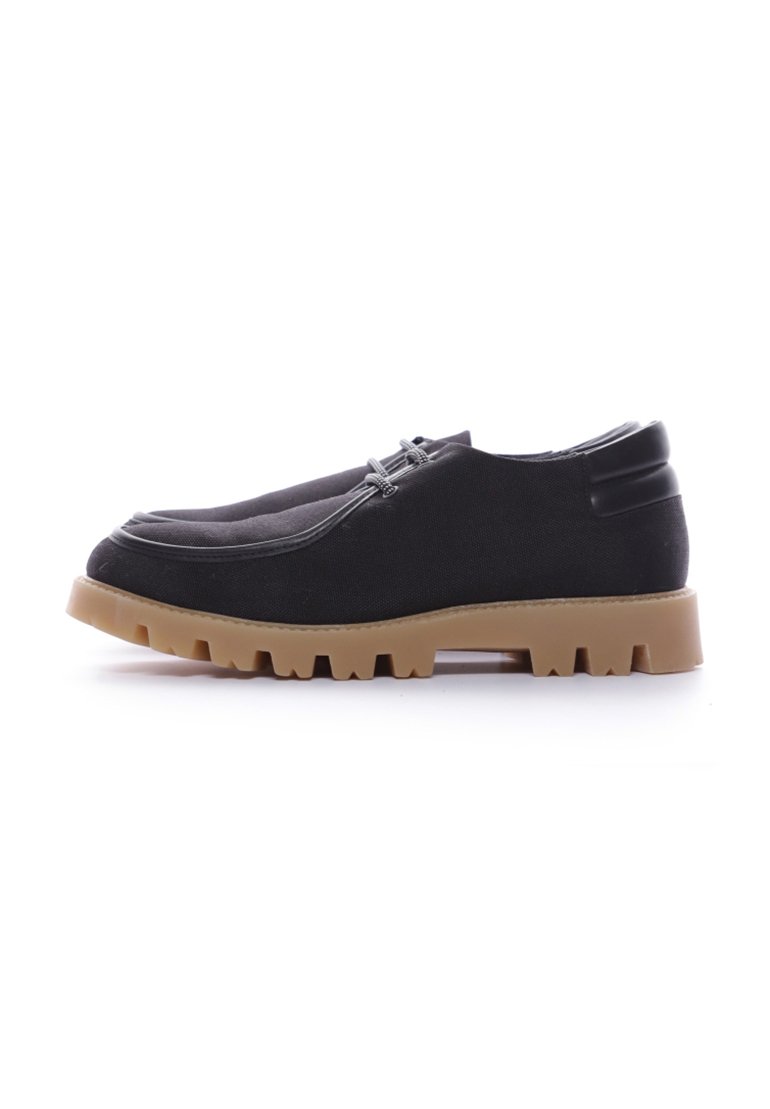 Scarpe da tela nere con una suola in gomma flessibile, caratterizzate da una punta rotonda e una parte superiore testurizzata, accentuate da dettagli in plastica scura.