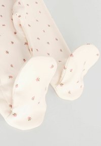 Ljusrosa leggings med fötter och små blommönster, med mjukt tyg och rundade fotändar. Fina rosafärgade tryckdetaljer genom hela.