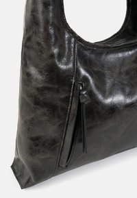Borsa hobo in pelle nera con una texture liscia e lucida. Presenta una tasca laterale con cerniera e una maniglia arrotondata. Design semplice e moderno.