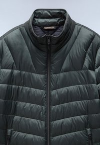 Vadderad jacka i mörkgrön, med hög krage, diagonalt quiltat mönster och en framdragkedja med sidofickor. Slät, glänsande yta.