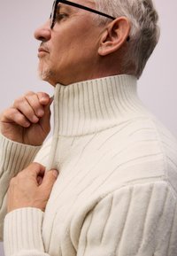 Suéter de punto grueso con un alto cuello acanalado, patrones diagonales texturizados y un cierre de cremallera.