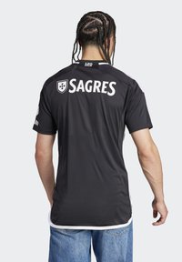 Maglietta sportiva nera con "SAGRES" stampato in bianco sul retro. Presenta maniche corte, scollatura rotonda e accenti bianchi sui lati.
