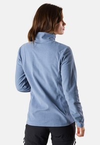 Giacca in pile azzurro chiaro con colletto alto, maniche lunghe e una texture liscia. Presenta un design aderente e una silhouette elegante.