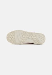 Talpa de sneaker din cauciuc off-white, cu modele texturate de striații și un design segmentat pentru aderență și flexibilitate. Accente subtile de roz.
