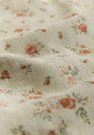 Világos bézs szövet apró narancs és zöld virágmintákkal. A textúra sima, látható átlós szövésmintával.