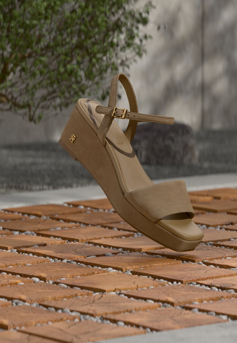 Μπεζ σαουέτ πλατφόρμα πέδιλο με ρυθμιζόμενο λουράκι αστραγάλου, σχέδιο ανοιχτής μύτης και λεπτομέρεια χρυσού εξαρτήματος, τοποθετημένο πάνω σε υφασμένη επιφάνεια.