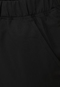 Schwarzer Stoff mit glatter Textur, ausgestattet mit einem elastischen Bund und subtilen Stichdetails. Keine sichtbaren Muster oder Metallelemente.