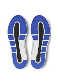 Suelas de zapatos con una superficie de goma azul con surcos texturizados, rodeadas de goma blanca. Incluye un acento de entresuela negra.