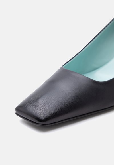 Γυναικείο μαύρο δερμάτινο επίπεδο παπούτσι με μυτερή τετράγωνη μύτη και εσωτερική επένδυση ανοιχτού γαλάζιου χρώματος σε λευκό φόντο.