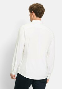 Langarm weißes Hemd mit klassischem Kragen, glatter Textur und geknöpften Manschetten. Verfügt über seitliche Schlitze und einen abgerundeten Saum hinten.