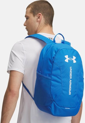 Zaino blu Under Armour dal design elegante, con spallacci regolabili e una tasca frontale con zip. Presenta il logo e un tessuto testurizzato.