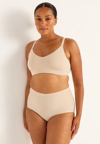 Beige sömlös bralette och högmidjade trosor. Mjukt, stretchigt tyg med en slät yta och minimal design. Justerbara band på braletten.