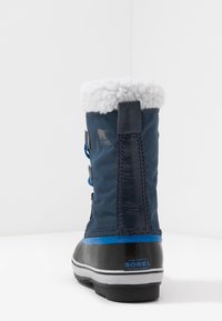 Granatowe wodoodporne botki z miękkim białym futerkiem na mankiecie, gumową podeszwą i ozdobnymi niebieskimi sznurówkami. Logo umieszczone z boku.