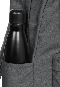 Black stainless steel water bottle partially visible in a gray fabric backpack pocket, with smooth texture and rounded cap.