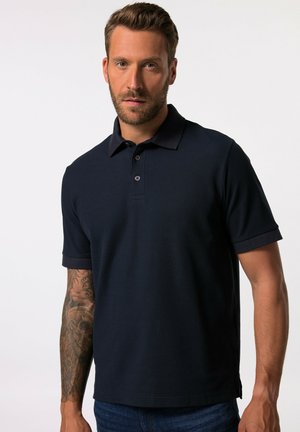 Camisa polo de color azul marino con mangas cortas, textura acanalada, tapeta de tres botones y un cuello sutil. Presenta un ajuste relajado.