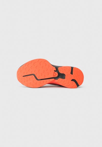 Sole boty má černý základ s živým oranžovým gumovým materiálem. Texturovaný grip se zigzagovými vzory a centrální drážkou pro trakci.