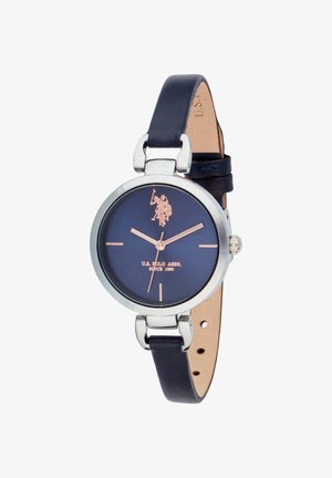 Orologio rotondo con quadrante blu navy, cassa color argento e dettagli in oro rosa. Dotato di cinturino in pelle blu navy con lato inferiore marrone chiaro.