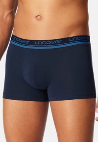 Mörkblå bomullsboxer med en bekväm midja som har "uncover"-logotyp i blått. Kort benlängd och en mjuk textur.