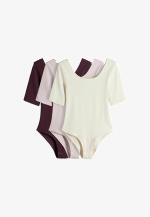 Kolme lyhythihaista potkupukua väriltään kerma, vaaleanpunainen ja tummanvioletti, aseteltuna vierekkäin valkoisella taustalla.