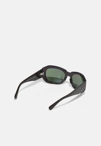 Ochelari de soare negri cu cadru unghiular, lentile verzi și brațe elegante. Prezintă detalii cu logo pe una dintre brațe și un accent cromat pe cadru.