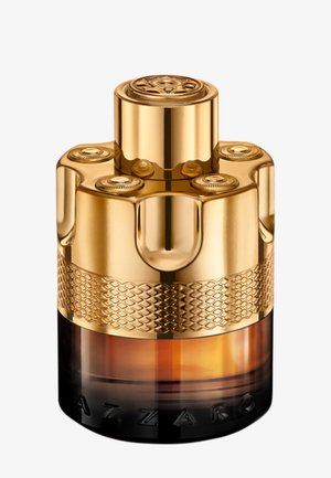 Botella de perfume cilíndrica dorada con acentos texturizados, tapa circular y base degradada de ambar a negro. Grabado de marca notable visible.