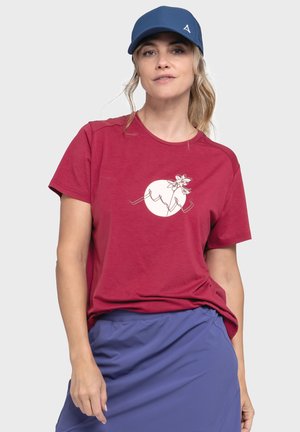 Bordeauxrotes T-Shirt mit kurzen Ärmeln und einem weißen grafischen Design, das eine Blume zeigt. Kombiniert mit einer blauen Mütze und einem blauen Rock. Glatte Textur.