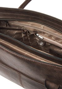 Interieur van een bruine leren handtas met een ritsvak en meerdere compartimenten. Voering heeft een subtiel monogrampatroon.