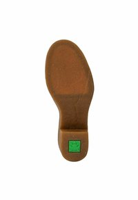 Suela de un zapato marrón con un logo cuadrado verde que presenta una rana en el talón, exhibida sobre un fondo blanco.