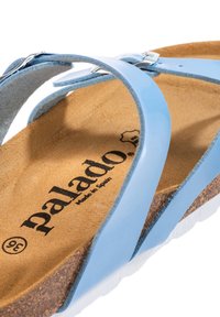 Světle modré gumové sandály se dvěma popruhy, korkovou stélkou, bílou podrážkou a tisknutým logem "palado" na texturovaném hnědém povrchu.