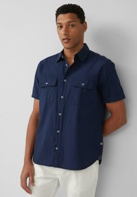 Kurzärmliges, marineblaues Hemd mit Knöpfen aus strukturiertem Stoff, zwei aufgesetzten Taschen vorne, hellblauen Knöpfen und abgerundetem Saum.
