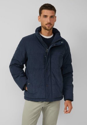 Veste matelassée bleu marine avec un col haut, fermeture éclair et boutons-pression. Présente un tissu texturé et deux poches latérales.