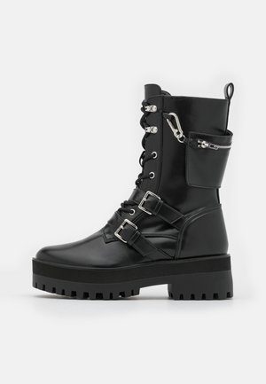 Czarne skórzane buty bojowe z przodem wiązanym na sznurówki, podwójnymi srebrnymi zapięciami, boczną kieszenią na zamek błyskawiczny oraz grubą gumową podeszwą z rowkowanym wzorem.