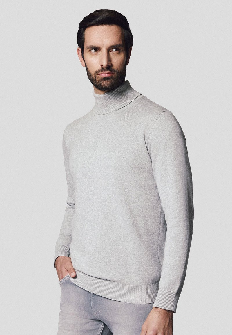 Jasnoszary sweter z golfem wykonany z miękkiej, teksturowanej tkaniny. Posiada dopasowany krój oraz ściągacze na mankietach i na dole.