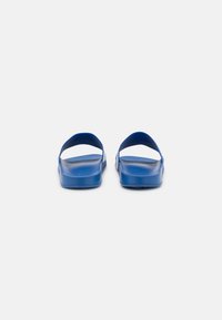 Blue slip-on sandals with a flat sole and two wide straps. Made of smooth material, featuring a simple and functional design.