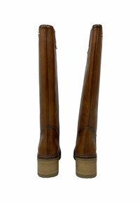 Botas de cuero marrón hasta la rodilla con punta redonda y tacón con plataforma. La parte trasera cuenta con una cremallera y un discreto detalle de costura.