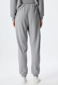 Pantaloni da jogging grigi in maglia con motivo testurizzato, vita elastica e polsini stretti, visti da dietro.