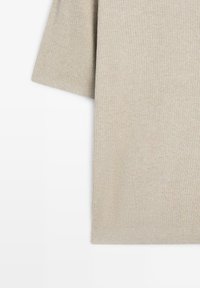 Haut beige à manches courtes en maille côtelée avec un ourlet droit, présenté sur fond blanc.