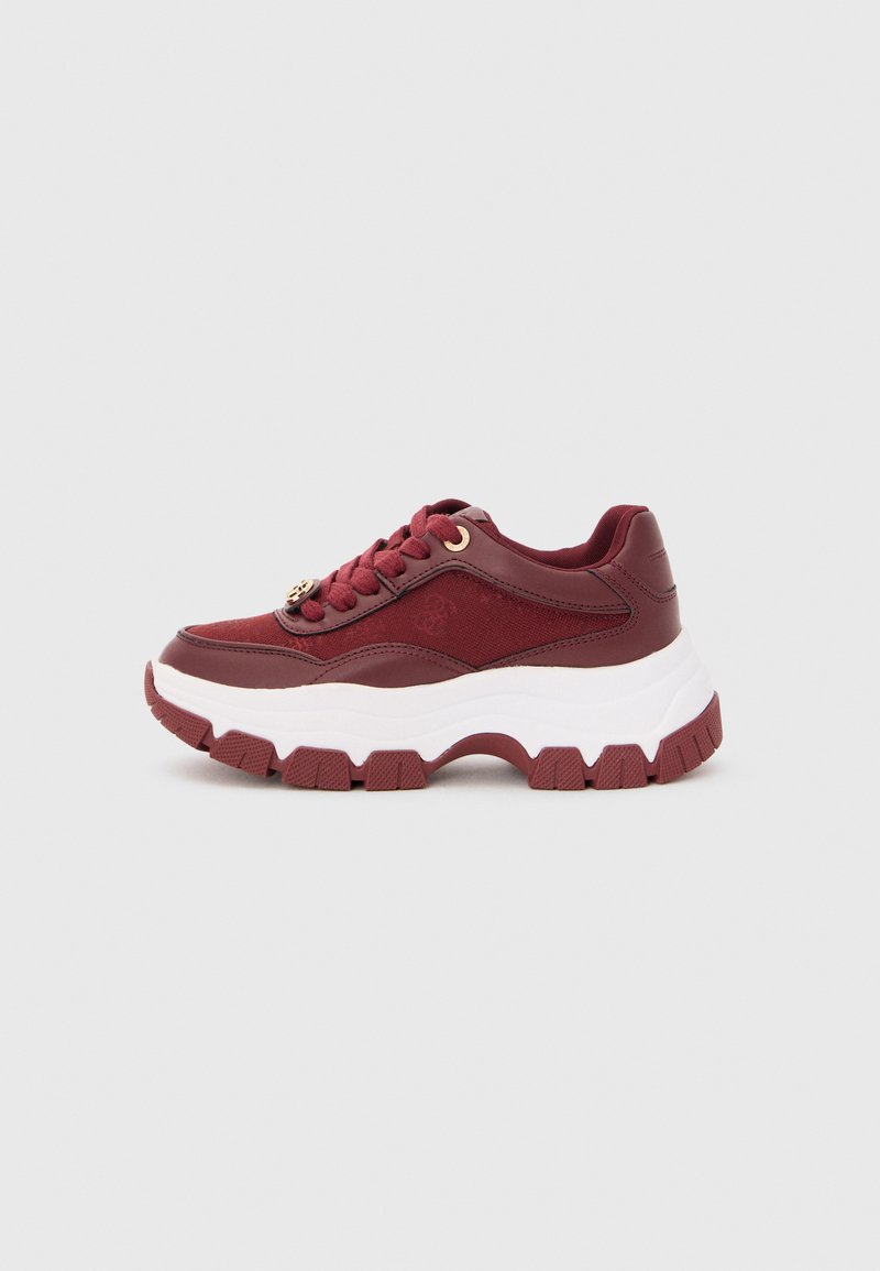 Sneaker bordeaux con suola bianca spessa, battistrada strutturato e lacci, posizionato su uno sfondo grigio chiaro uniforme.
