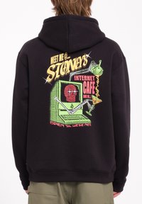 Haut à capuche noir avec un graphique coloré dans le dos, représentant un ordinateur vintage avec un crâne et le texte "Rendez-vous chez Stoney's Internet Cafe."